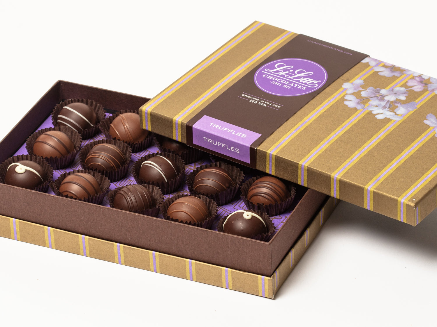 A rectangular box containing fifteen assorted truffles. The box is gold with narrow purple stripes. The lid is the same gold striped pattern with a spray of watercolor lilacs. The chocolate ganache truffles inside the box are assorted flavors in milk and dark chocolate.