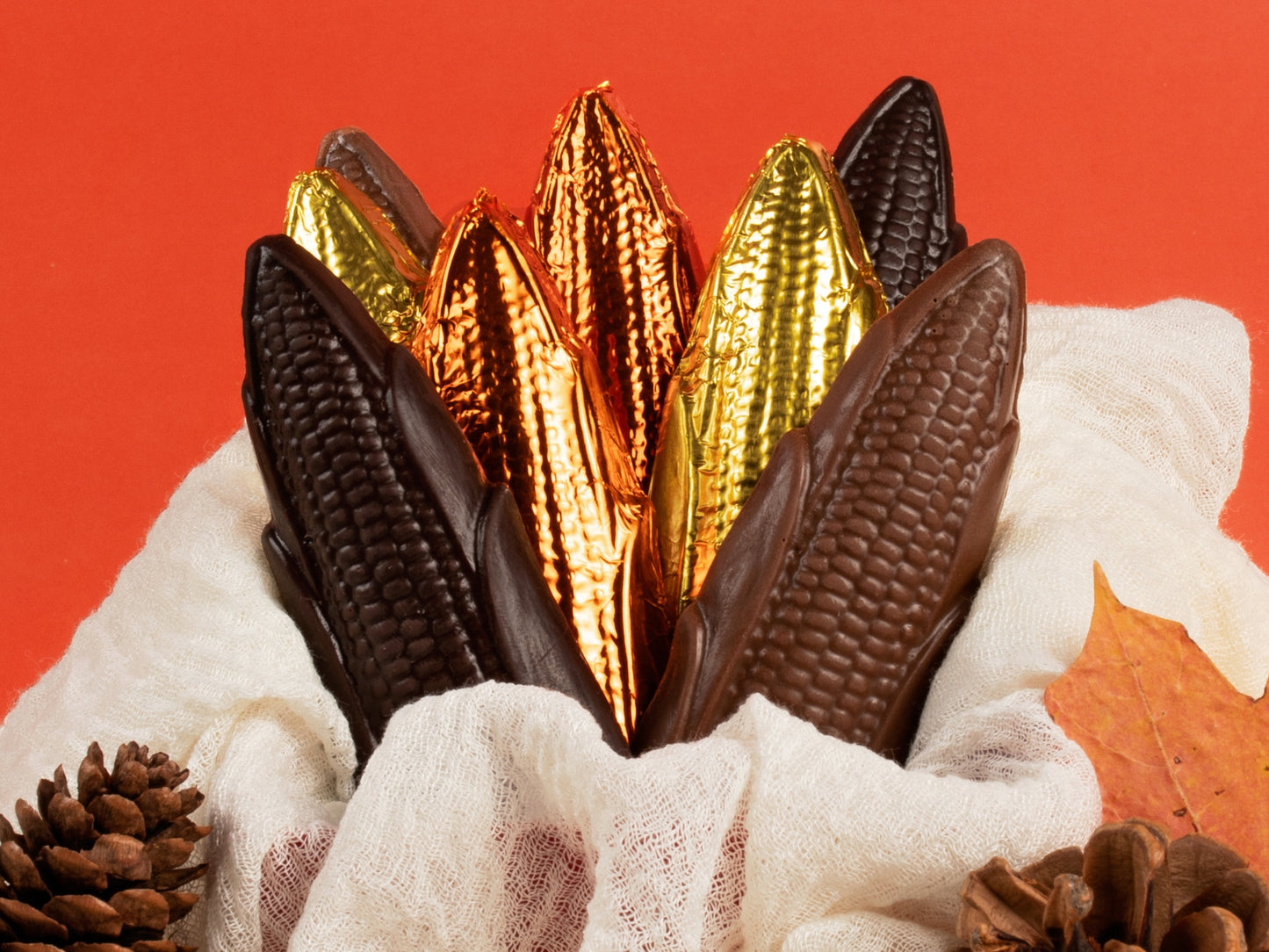 Molded chocolate ears of corn are wrapped in foil. Milk chocolate is wrapped in gold foil and dark chocolate is wrapped in orange foil.