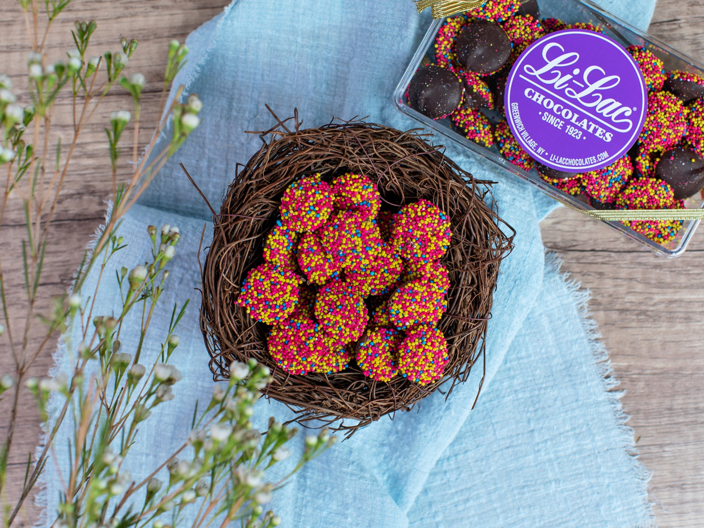 A nest filled with chocolate Easter Nonpareils and a clear box with Easter Nonpareils behind it.