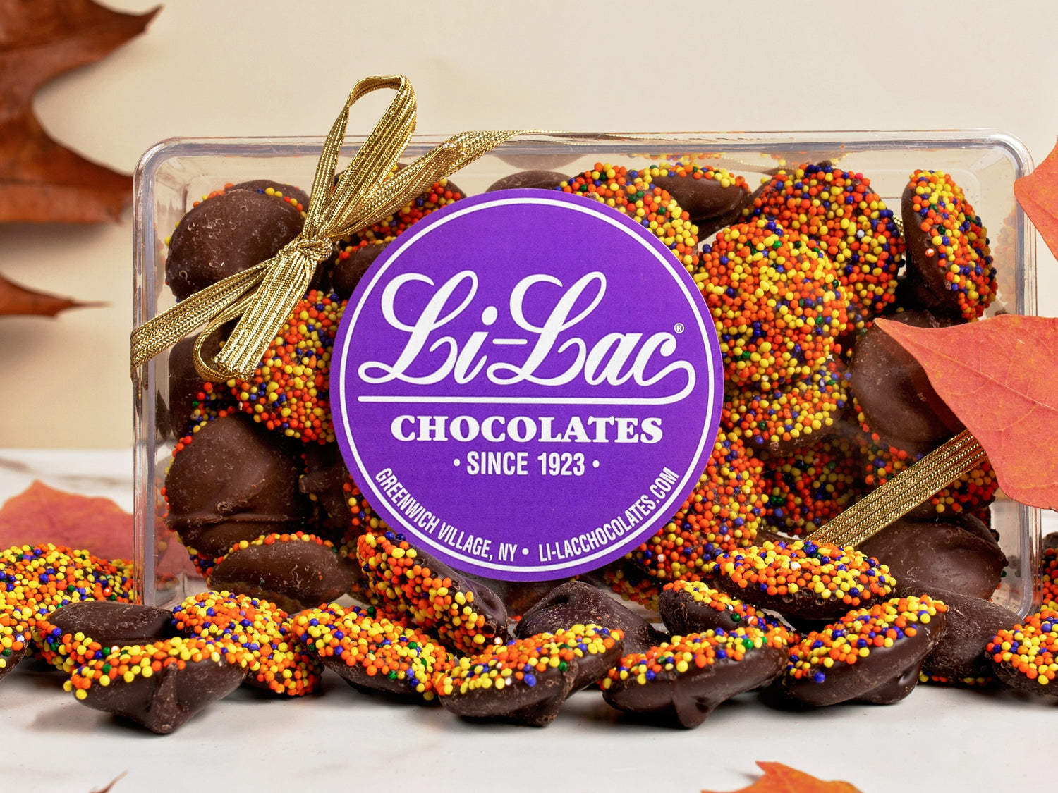 Thanksgiving colored Nonpareils in a clear box with a Li-Lac Chocolate round sticker on the lid. 