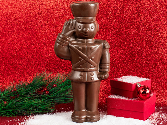 A large molded chocolate toy soldier stands at attention, saluting.