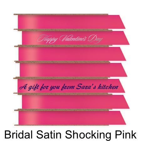 A stack of seven spools of shiny bright pink satin ribbon with custom messages printed on them in different colors. 