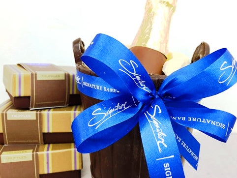 Custom printed ribbon has your words or logo printed into it. This example is a bright blue ribbon with Signature Bank embossed in silver foil letters.