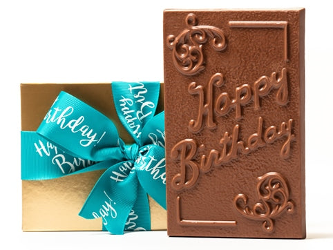 A large chooclate bar that has filigree decorations and the greeting "Happy Birthday" embossed in the chocolate mold. It comes in a gold box with an aqua ribbon with Happy Birthday printed on it.