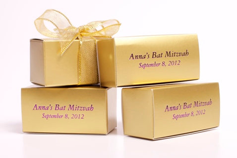 Little gold cardstock boxes have printed messages on the lid and tied with a gold ribbon.